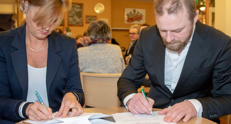 Foto: twee mensen aan tafel die schrijven