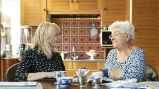 foto van twee mensen die praten aan de keukentafel