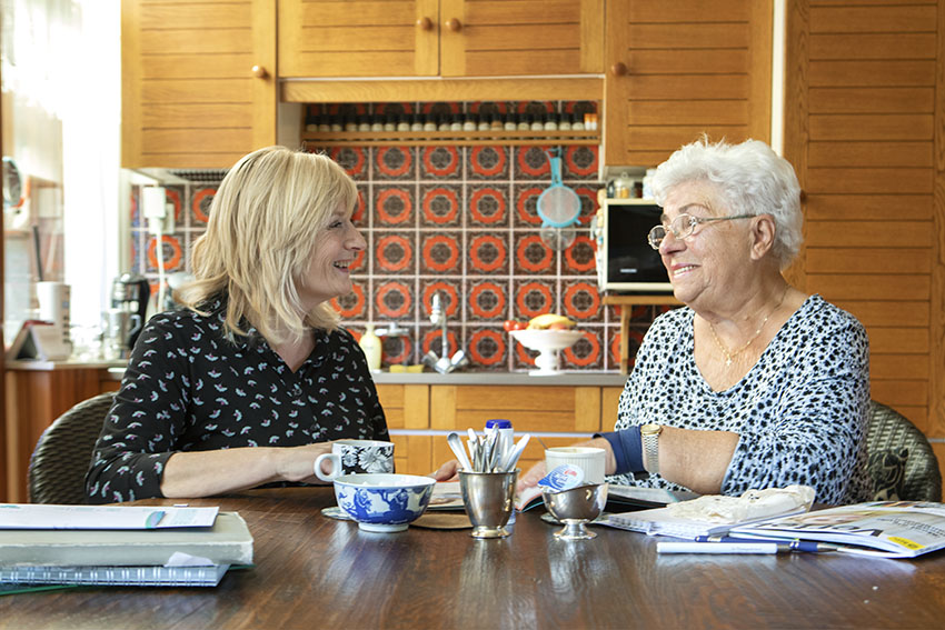 foto van twee mensen die praten aan de keukentafel