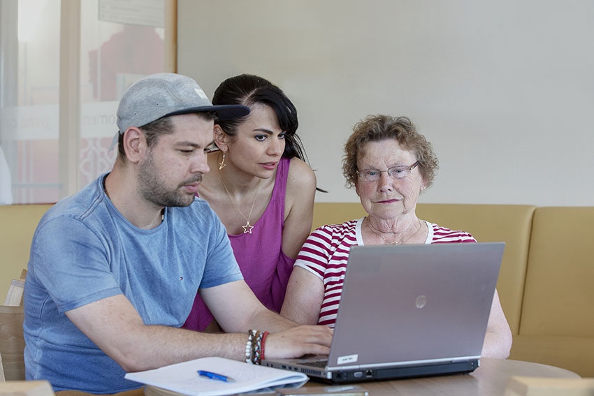 foto van twee vrijwilligers van Stip Midden en een mevrouw die achter een laptop zitten