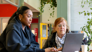 foto van een stip medewreker met een bewoner achter een laptop