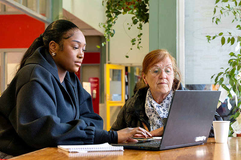 foto van een stip medewreker met een bewoner achter een laptop
