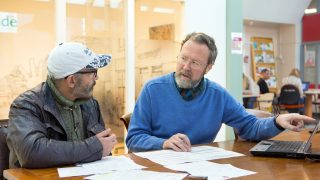 Foto: een medewerker van de Stip geeft uitleg aan een bezoeker van de Stip