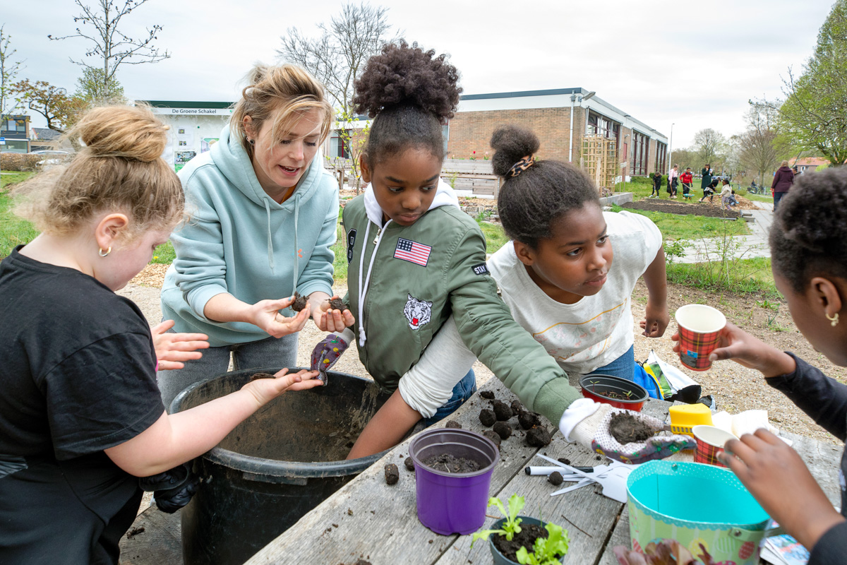 Foto van kinderwerker en kinderen maken zaadbommetjes