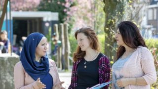 drie vrouwen in gesprek op een schoolplein