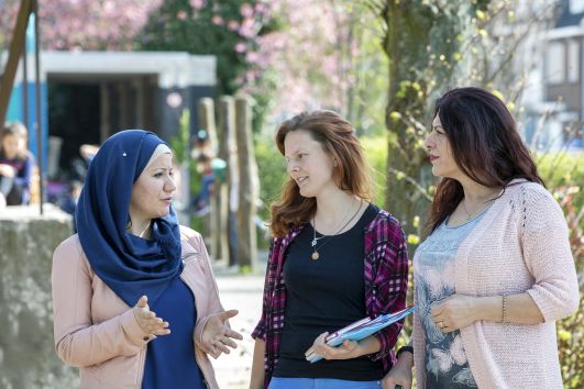 drie vrouwen in gesprek op een schoolplein