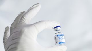 foto van een hand met flesje vaccin