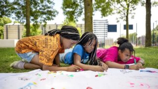 foto van drie meiden die tekenen in een park