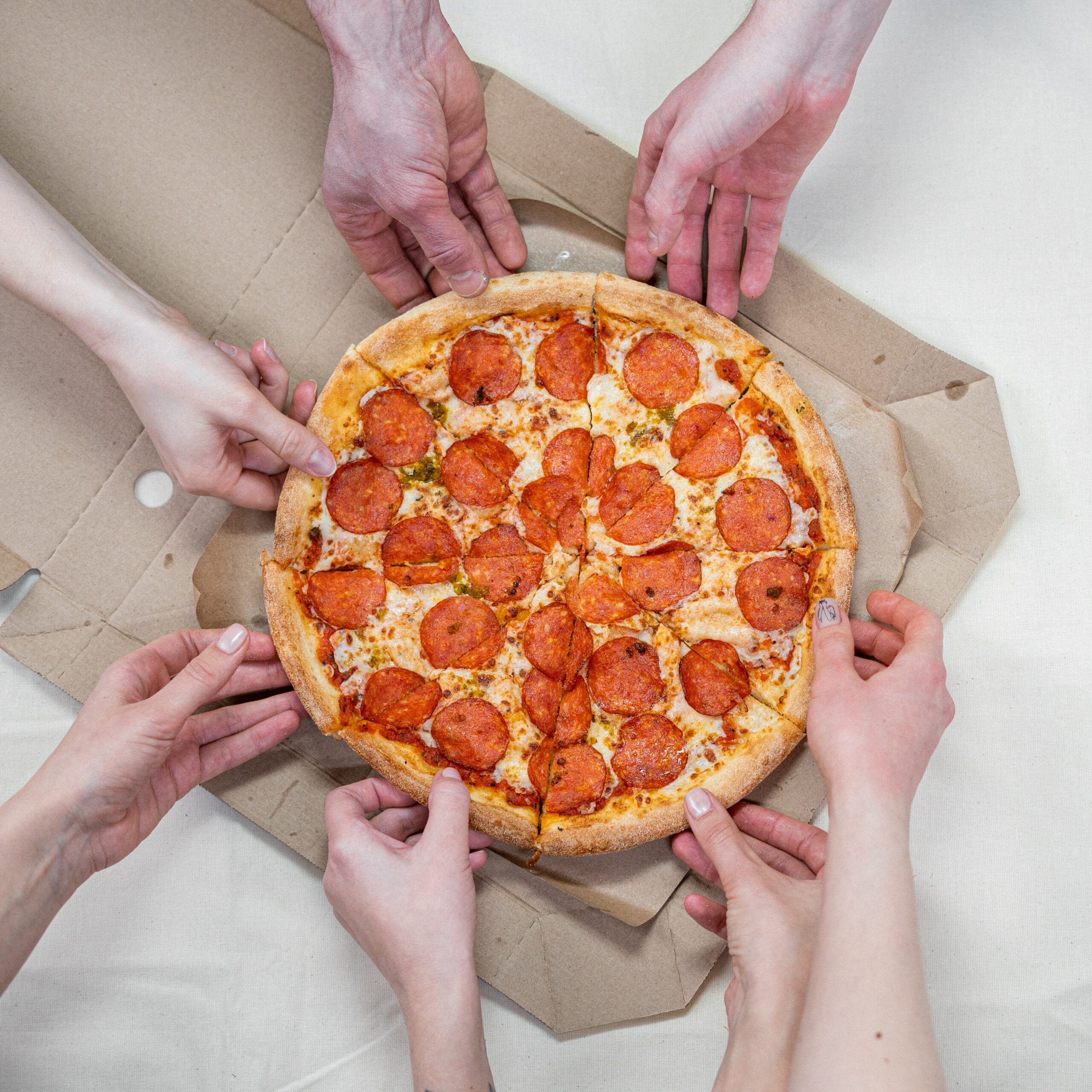 foto van handen die slices van een pizza pakken