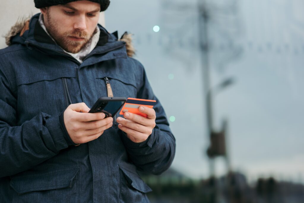 foto van een man met ene telefoon en een baknpas in zijn handen