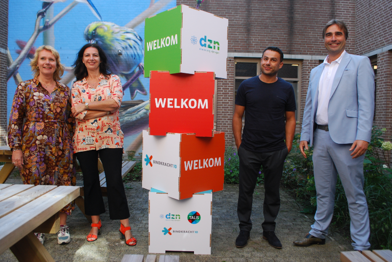 bestuurders van Talis, Bindkracht10 en DZN bij een toren van blokken met hun logos erop.