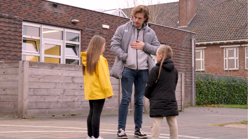 Foto van een kinderwerker met twee kinderen in de wijk