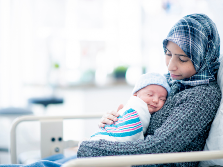 Vrouw met hoofddoek met baby op de buik in het ziekenhuis aan het rusten