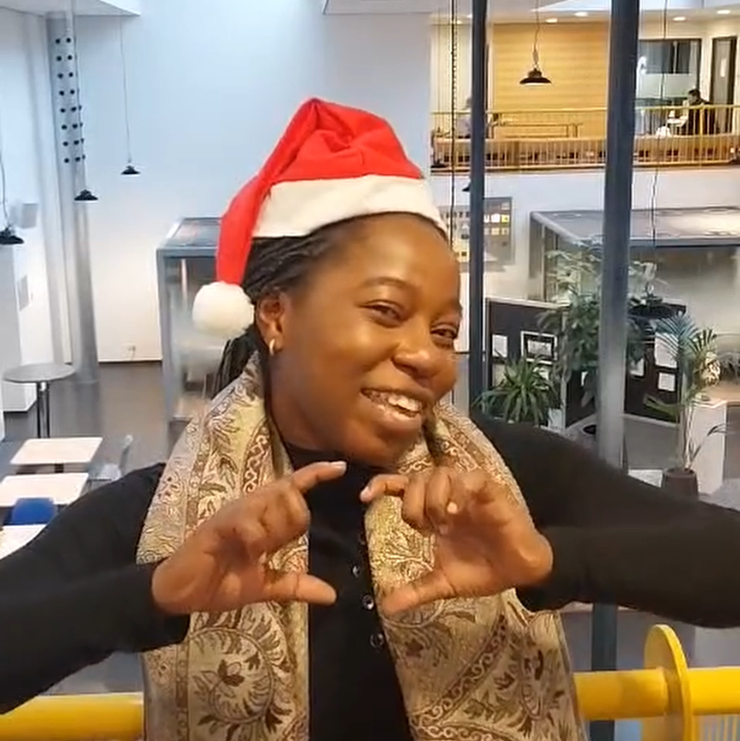 Medewerkers met kerstmuts die een hartjesgebaar maakt