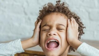 kind met handen over oren