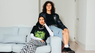 Twee jonge vrouwen op een bank kijken de kijker aan