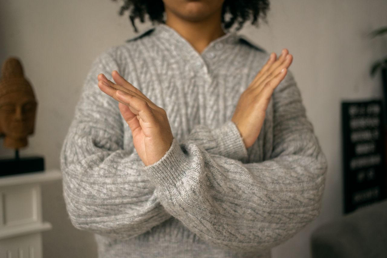 een vrouw kruist haar armen voor haar lichaam als Nee gebaar